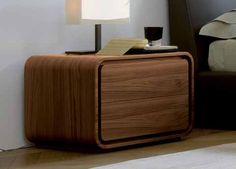 a nightstand with a lamp on top of it next to a bed