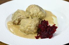 meatballs covered in gravy and cranberry sauce on a white plate