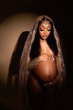 a pregnant woman wearing a veil and holding her belly in front of a dark background