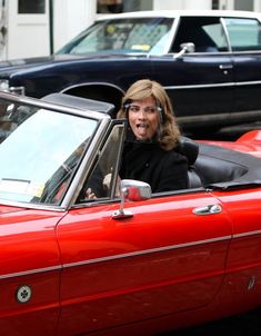 a woman is sitting in the driver's seat of a red car