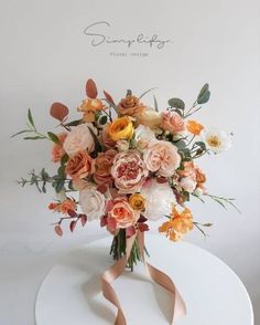 a bouquet of flowers sitting on top of a white table with a pink ribbon around it