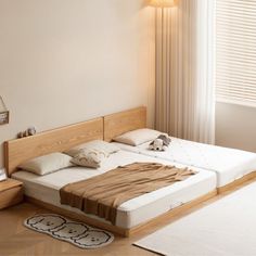 a bed room with two beds and a rug on the floor in front of a window