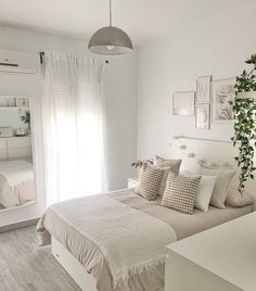 a bedroom with white walls and wood flooring is decorated in neutral tones, including beige bedding