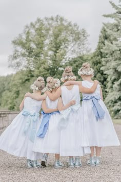 the bridesmaids are dressed in white dresses and blue sashers, with their backs to the camera