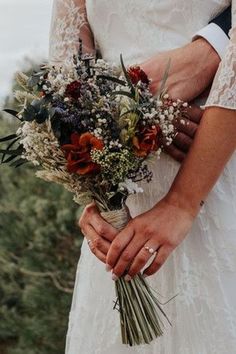 a bride and groom holding each other close to the camera with their wedding bouquet in hand