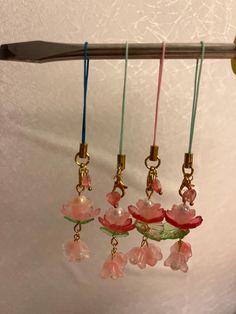 four glass flowers hanging from hooks on a wall