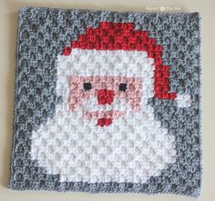 a crocheted square with a santa clause on it's face and red hair