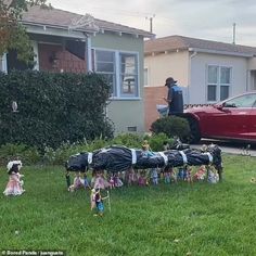 a group of people standing in front of a house next to a yard filled with toys