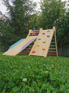 a wooden slide and climbing wall in the grass