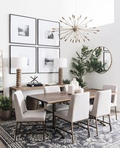 a dining room table and chairs with pictures on the wall above it, along with potted plants