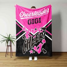 a woman standing in front of a pink and black towel with the words cheerleader on it