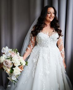 a woman in a wedding dress is holding a bridal bouquet and smiling at the camera