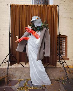 a woman dressed as a bird in front of a stage with lights and curtains behind her