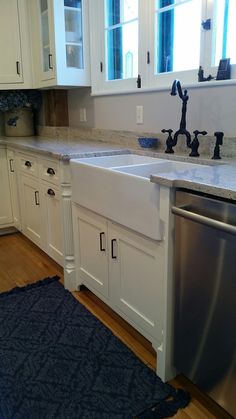 a kitchen with white cabinets and blue rugs on the hardwood floor next to the sink