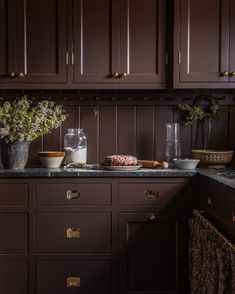 a kitchen with brown cabinets and marble counter tops, flowers in vases on the sink