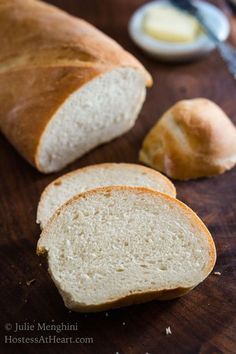 two loaves of bread sitting on top of a wooden cutting board next to butter