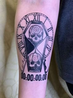 a person with a tattoo on their arm has a clock in the shape of a skull