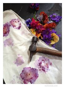 flowers and an old hammer are laying on the ground next to a cloth that has been dyed purple