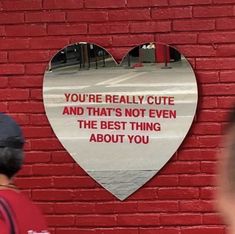 a heart shaped sign on the side of a red brick wall that says, you're really cute and that's not even the best thing about you