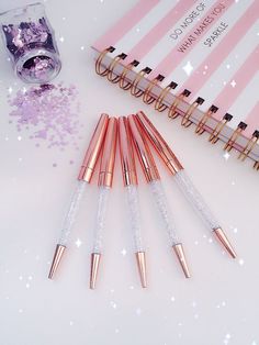 five pink and white makeup brushes sitting on top of a table next to a notebook