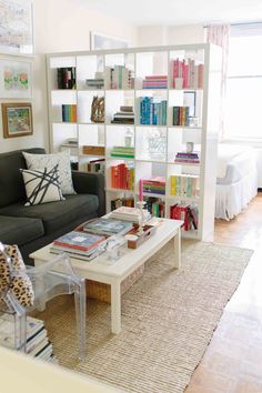 a living room filled with furniture and bookshelves next to a white coffee table