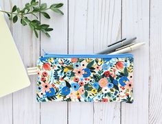 SIZE: 8" wide x 4" tall COLOR FRONT: Rifle Paper Co Wildwood Garden Party Blue COLOR BACK:  Rifle Paper Co Wildwood Garden Party Blue INSIDE: Blue Stripe This cute floral zipper pouch is 100% handmade by me   Pencil or pen zipper pouch is perfect to tuck into your purse.  So many uses.  Not too big and not too small.  You can never have too many.  Great for organization, school stuff, money, goodies, etc. Each bag is lightly padded for durability.  Nylon zipper and coordinating fabric inside. Yo Blue Pencil Case With Zipper Closure As Gift, Garden Party Blue, Organization School, Pen Pouch, Pencil Bag, Pencil Bags, Coordinating Fabrics, Zipper Bag, Purse Pouch