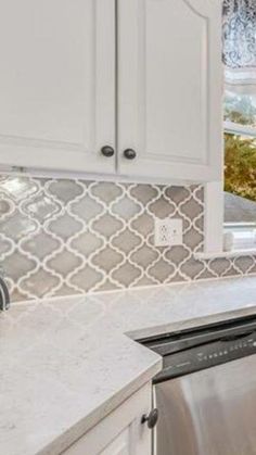 a kitchen with white cabinets and stainless steel dishwasher