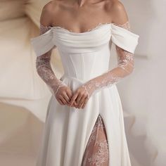 a woman in a white wedding dress with sheer sleeves and thigh high slited stockings