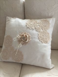 a white pillow with crocheted flowers on it