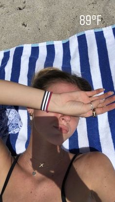 a woman laying on top of a blue and white towel next to a person with their hand over her face