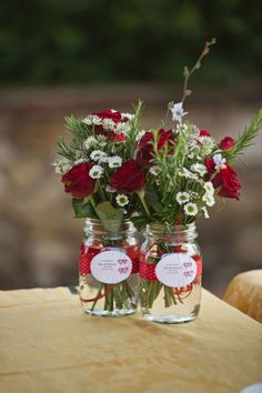 two mason jars filled with red and white flowers