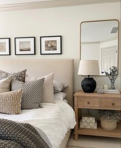 a bedroom with a bed, mirror and pictures on the wall above it's headboard