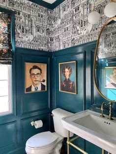 a bathroom decorated in teal and gold with pictures on the wall above the toilet