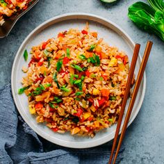 a white plate topped with rice and vegetables next to chopsticks