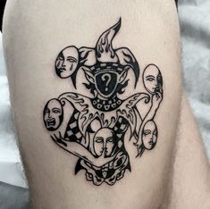 a black and white tattoo on the thigh of a man's leg with faces