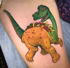 a tattoo with a dinosaur on it's leg