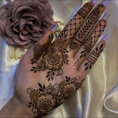 a woman's hand with henna on it and a flower in the background