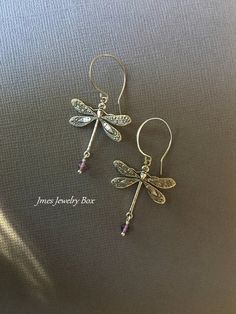 Beautiful silver dragonfly earrings with amethyst beads. Very detailed silver dragonflies are on handmade stainless steel ear hooks. Total earring length is just under 2 inches. *Silver plated brass dragonflies *Stainless steel ear hooks *Faceted amethyst beads *Handmade with love <3 Like Jmesjewelrybox on Facebook for updates on new jewelry, upcoming sales and giveaways! Plus Facebook fans save 5% :D Find the coupon code on Jmesjewelrybox's cover photo https://www.facebook.com/Jmesjewelrybox Purple Pierced Metal Jewelry, Purple Metal Pierced Jewelry, Elegant Sterling Silver Dragonfly Jewelry, Dainty Silver Dragonfly Jewelry, Silver Amethyst Wire Wrapped Earrings, Dainty Sterling Silver Dragonfly Jewelry, Nickel-free Dragonfly Sterling Silver Earrings, Nickel-free Sterling Silver Dragonfly Earrings, Dragonfly-shaped Pierced Earrings As Gift