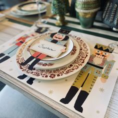 a place setting with plates and napkins on a tablecloth that is decorated with nutcrackers