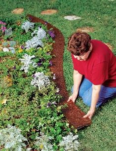 a person kneeling down in the grass with some plants growing out of it and dirt on the ground