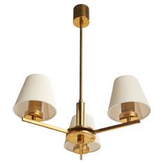 three light brass chandelier with white shades on the top and bottom lights in gold