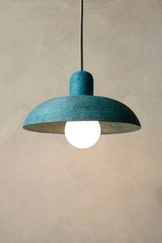 a blue lamp hanging from a ceiling in a room with concrete walls and flooring