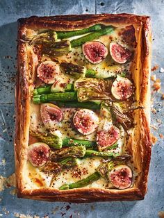 a pizza with asparagus and other toppings on a baking sheet, ready to be eaten