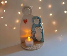 a lit candle is sitting next to a ceramic figurine with a heart on it