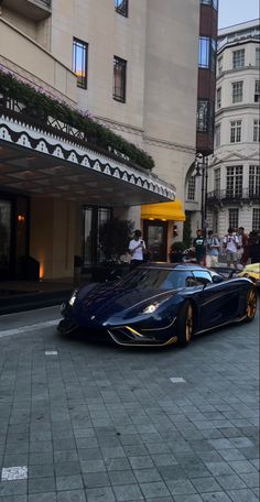 a blue sports car parked in front of a building on a city street with people walking by