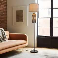 a living room with a couch, table lamp and brick wall in the back ground