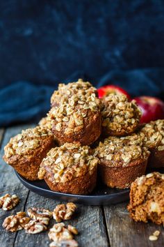 some muffins are on a plate with apples in the background