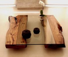 a glass table with two wooden pieces on it and a flower in a vase next to it