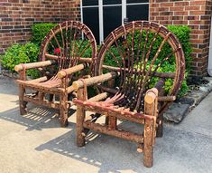 two wooden chairs sitting next to each other in front of a brick building with plants growing out of them