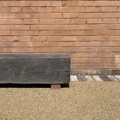 a wooden bench sitting in front of a brick wall